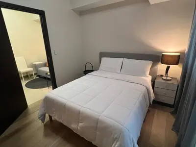 a bedroom with a large white bed and a mirror at Parkwest McKinley - 1 Bedroom Fully Furnished in Manila