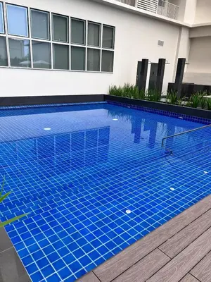 a blue swimming pool in front of a building at Parkwest McKinley - 1 Bedroom Fully Furnished in Manila