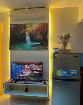a television in a room with a painting on the wall at MOA Shell Residences Staycation in Manila