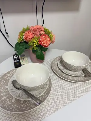 a table with two plates and a vase with flowers at Shore Residences Banana Room with 2 Beds Good for 4 Guests Pool View Room 622 by Prime Stay in Manila
