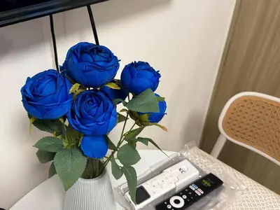 a vase filled with blue roses sitting on a table at Shore Residences near Airport Blueberry Room 2 Beds Pool View by Prime Stay Room 628 in Manila