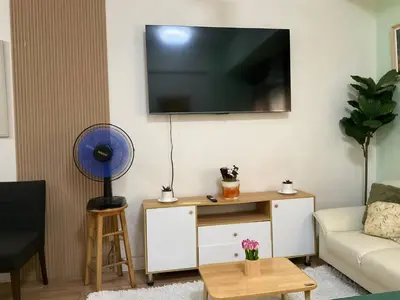 a living room with a couch and a tv on a wall at Seb and Santi Holland Park Staycation in Biñan