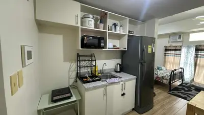 a small kitchen with a refrigerator and a sink at Seb and Santi Holland Park Staycation in Biñan