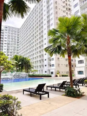 a large building with a pool and a palm tree at SHORE 2 TOWER 2 NEAR MOA 16TH Floor in Manila