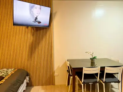 a dining room with a table and a tv on the wall at Casa Haraya Urban Stays - Walking Distance to NAIA Terminal 3 Newport City Condo with 500mbps WIFI and free Netflix access in Manila