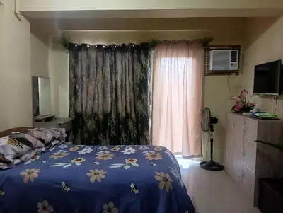 a bedroom with a bed with a blue comforter and a window at Deviente's Guesthouse in Manila