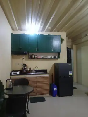 a kitchen with green cabinets and a table in a room at Deviente's Guesthouse in Manila