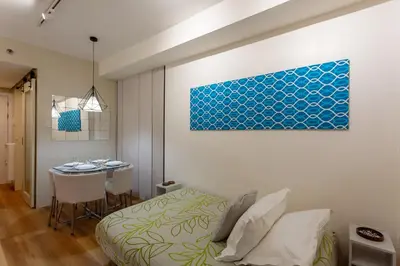 a bedroom with a bed and a table and a painting at Sparkling Shell Residences Kaeri Properties in Manila