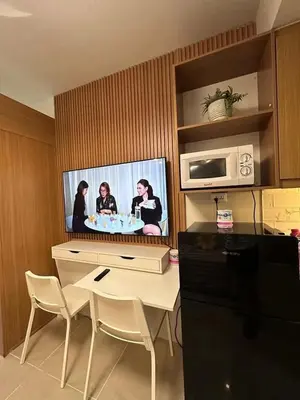 a kitchen with a tv and a table with chairs at Staycation, Mall of Asia in Manila