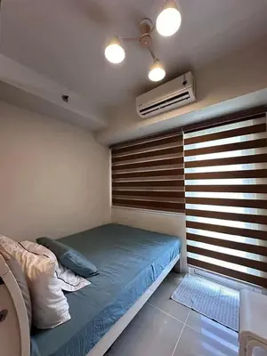 a small bedroom with a bed and a window at Staycation, Mall of Asia in Manila