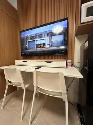 a tv sitting on top of a desk with two chairs at Staycation, Mall of Asia in Manila