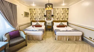 a hotel room with two beds and a chair at Miramar Hotel in Manila