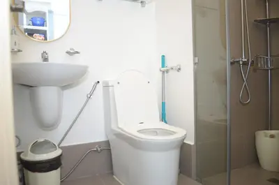 a bathroom with a toilet and a sink and a mirror at Modern 1 bedroom w Pool and City Views in Manila