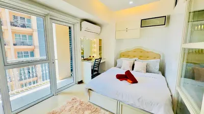 a bedroom with a bed and two large windows at AdahkuMaya Luxury Suites in Manila