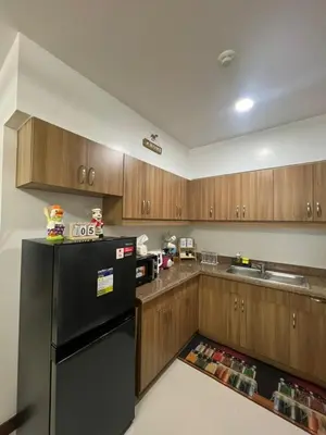 a kitchen with a black refrigerator and wooden cabinets at Mysuites2go 517 Lenden in Manila