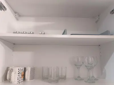 a shelf with wine glasses on a white wall at Makati City Ph SnowWhite Staycation in Manila