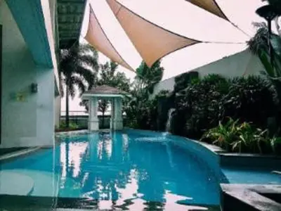 a swimming pool with an umbrella next to a building at The orienthal place, Makati a1 in Manila