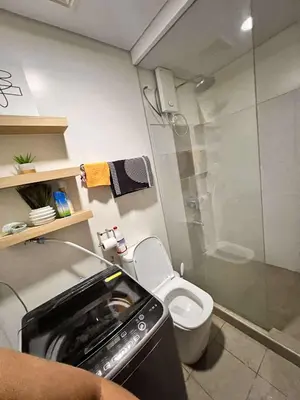 a bathroom with a toilet and a glass shower at The Olive Place, Manadaluyong City in Manila