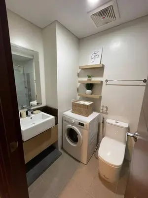a bathroom with a toilet and a sink and a washing machine at The Olive Place, Manadaluyong City in Manila