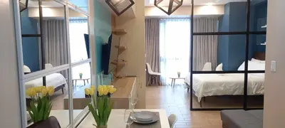 a living room with a bed and a table with flowers at Megaworld in Manila