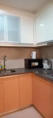 a kitchen with white cabinets and a black microwave at Megaworld in Manila