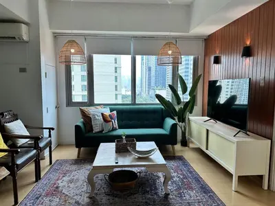 a living room with a green couch and a table at Cozy House BGC 1BR up to 6 Guests 100MBPS WiFi in Manila