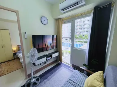 a living room with a tv and a large window at Amber's Crib in Manila