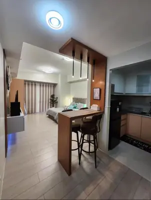 a kitchen and living room with a table and a bed at Cozy Condo Unit Near NAIA Terminal 3 in Manila