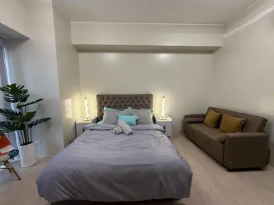 a bedroom with a large bed and a couch at Cozy Condo Unit Near NAIA Terminal 3 in Manila