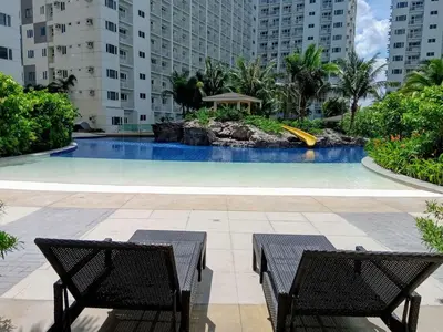 a swimming pool in a building with two chairs at Shore 1 Residences - ÜniQa Suite - MOA Area in Manila
