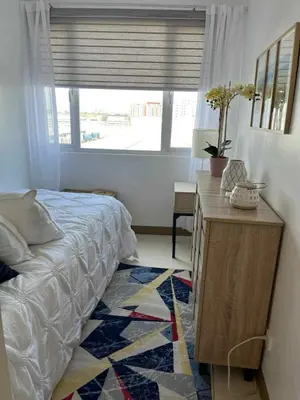 a bedroom with a bed and a desk and a window at South Residences Tower 4, Las Pinas in Manila