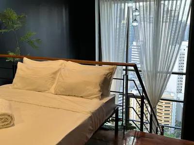 a bed with white sheets in a room with a window at Stylish 100 SQM 3BR Loft Near Greenbelt Makati in Manila