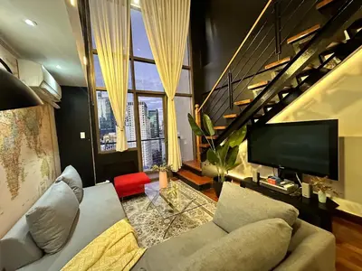 a living room with a couch and a large window at Stylish 100 SQM 3BR Loft Near Greenbelt Makati in Manila
