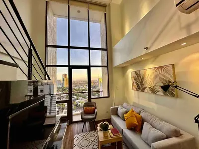 a living room with a couch and a large window at Huge 100-SQM 3BR Loft near Greenbelt Makati in Manila