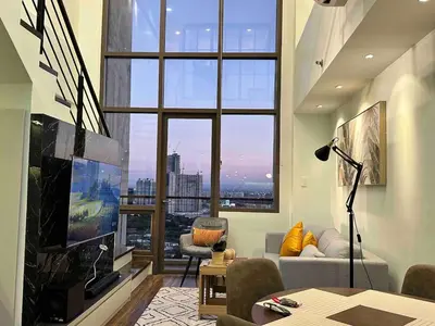 a living room with a large window and a tv at Huge 100-SQM 3BR Loft near Greenbelt Makati in Manila