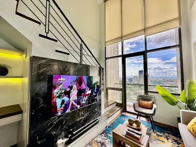 a living room with a large tv and a large window at Huge 100-SQM 3BR Loft near Greenbelt Makati in Manila