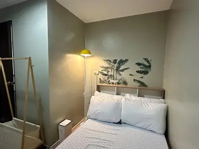 a bedroom with a bed with a lamp on the wall at 100 SQM 3BR in Central Makati Greenbelt Area in Manila