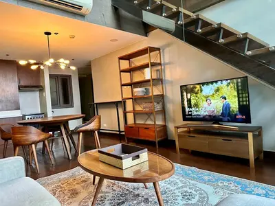 a living room with a couch and a tv and a table at 100 SQM 3BR in Central Makati Greenbelt Area in Manila