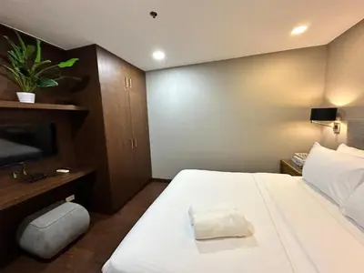 a bedroom with a large white bed with a plant on it at 100 SQM 3BR in Central Makati Greenbelt Area in Manila