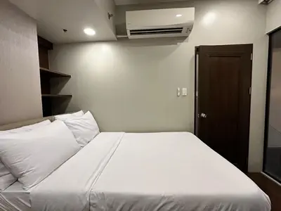 a bedroom with a large bed with white sheets at 100 SQM 3BR in Central Makati Greenbelt Area in Manila