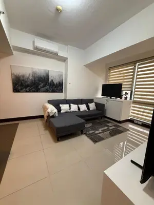 a living room with a couch and a tv at Executive Suites Bellagio Golf View Residences in Manila