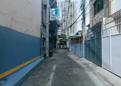 an empty alley in a city with buildings at Maine Residences Leveriza by RedDoorz in Manila