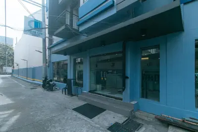 a blue building with glass windows on a street at Maine Residences Leveriza by RedDoorz in Manila