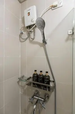 a shower with a shower head and bottles on a shelf at Luxurious Studio in McKinley Hill with City View in Manila