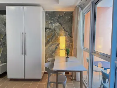 a dining room with a table and chairs and a stone wall at PREMIUM 1BR Venice Canal Mall, Pool, Gym, Sauna & 5G Wi-Fi, Ste 16 in Manila