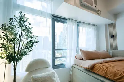 a bedroom with a bed and a large window at Breathtaking Eastwood City View, 3min walk to Malls, with Washer in Manila