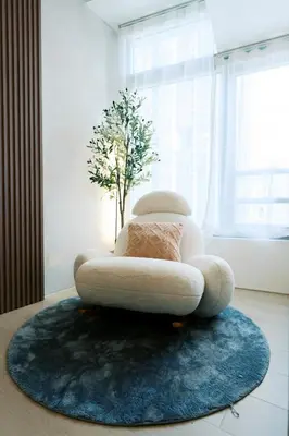 a white chair sitting on top of a blue rug at Breathtaking Eastwood City View, 3min walk to Malls, with Washer in Manila