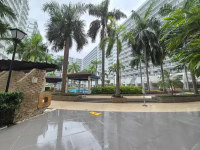 a courtyard with palm trees in front of a building at Family Suite with Big Balcony and Pool View in Manila