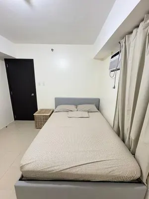 a bed sitting in a room next to a window at City Lights and Cozy nights in Manila