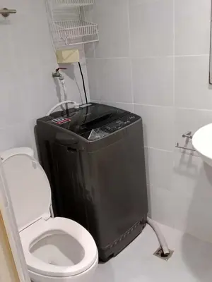 a bathroom with a toilet and a black trash can at SEA RESIDENCES Golden in Manila